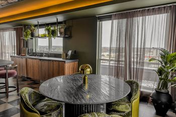 A round table with a gold handle sits in the middle of a room with a bar and chairs.